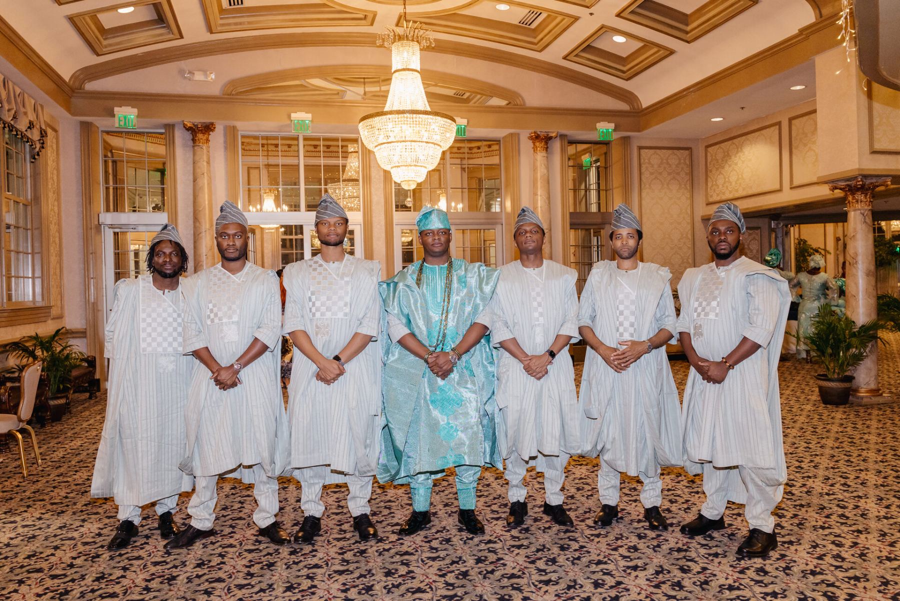 The seven in traditional agbada, the groom in teal at the center