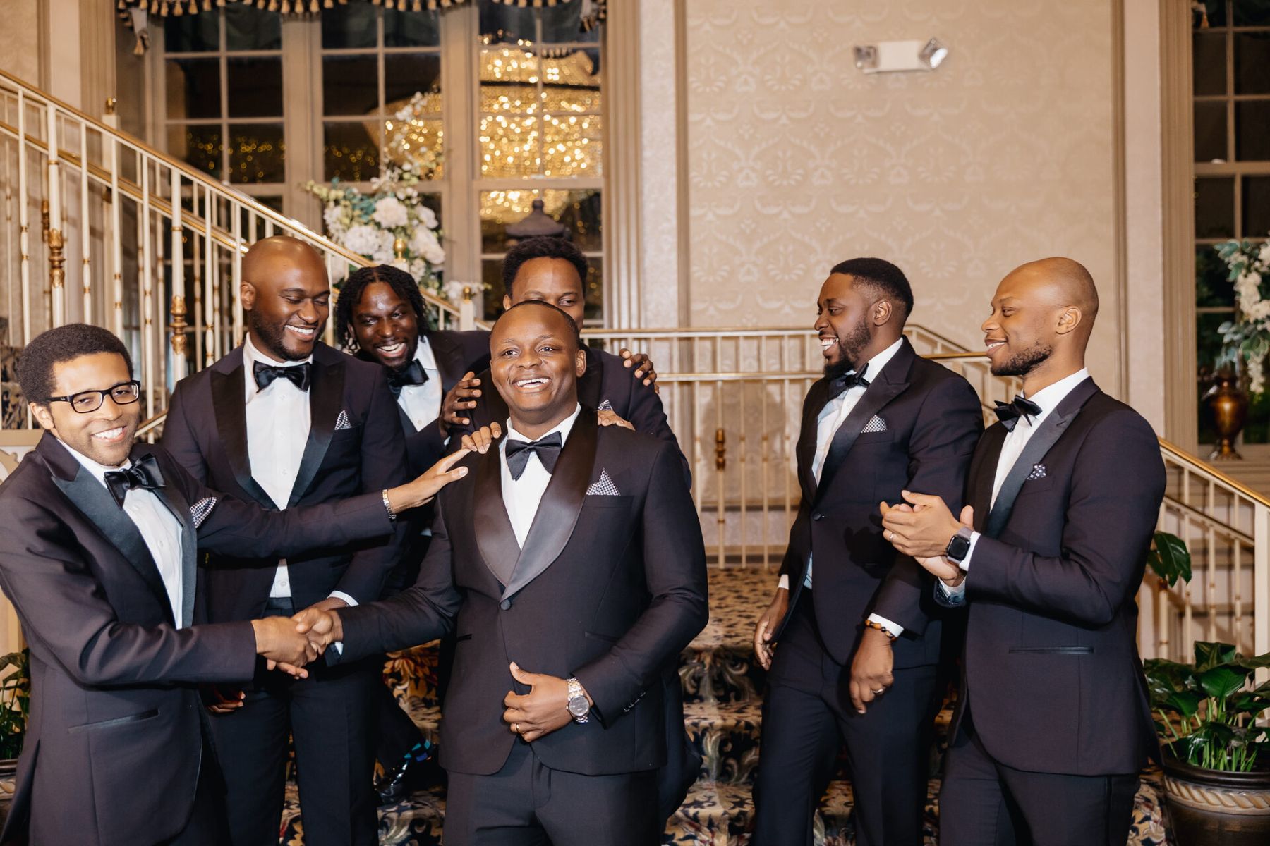 The crew laughing on the staircase, teasing the groom, wedding day