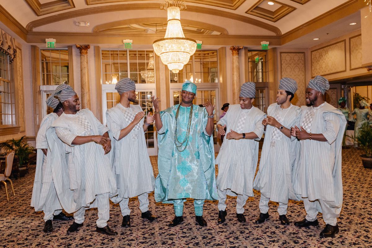 The crew in agbada mid-dance around the groom