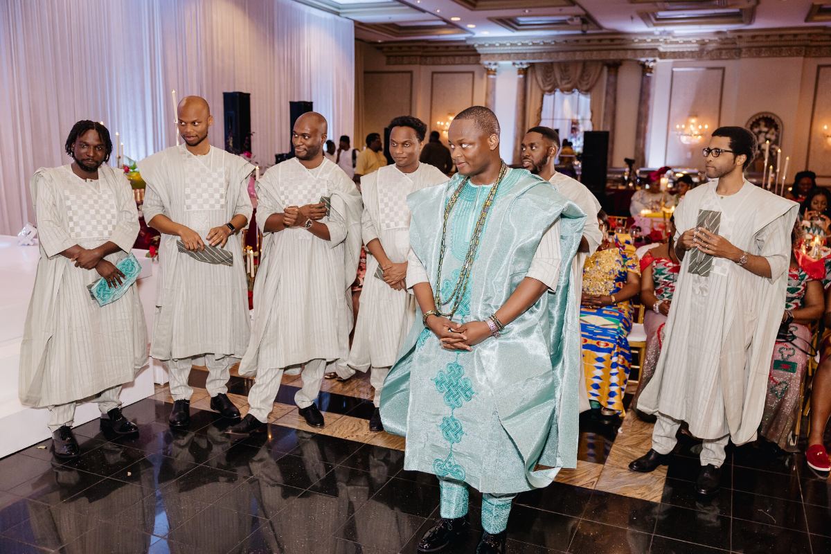 The crew in agbada, hands on the groom's shoulders